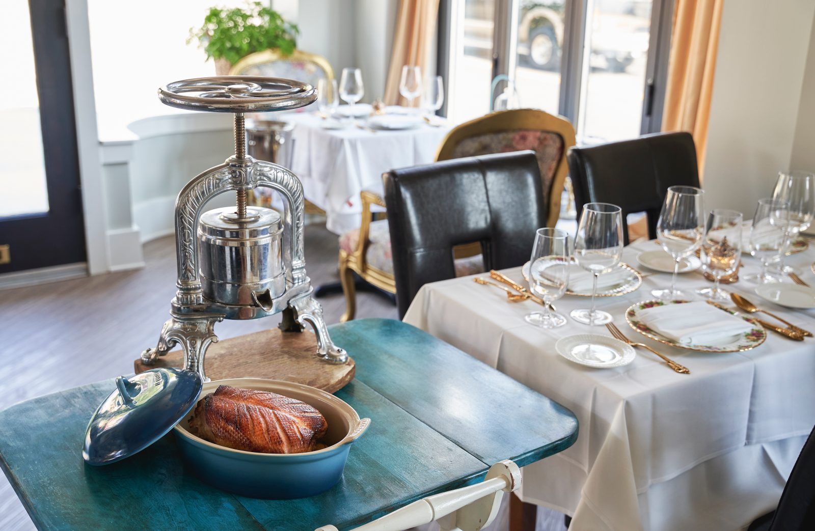 The June BYOB dining room, with an antique French duck press set on a service cart beside a laid table